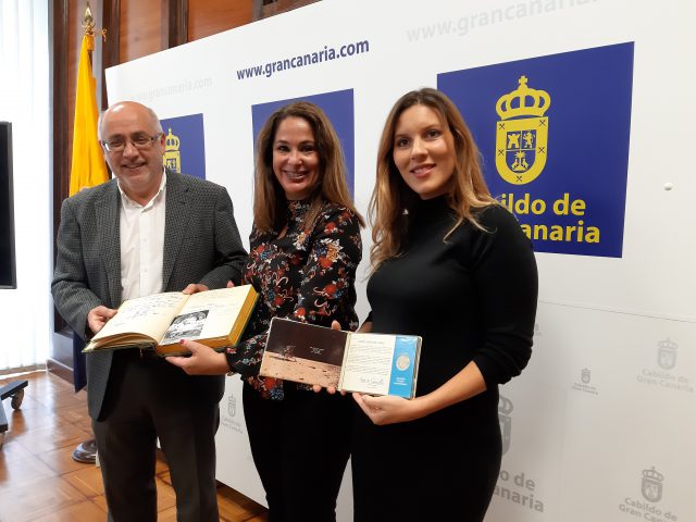 Antonio Morales Elena Espino y Laura García muestran el libro del hotel Maspalomas Oasis con la firma de los astronautas en 1969