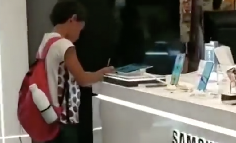 Un niño utiliza la tablet de un expositor para hacer los deberes en una tienda