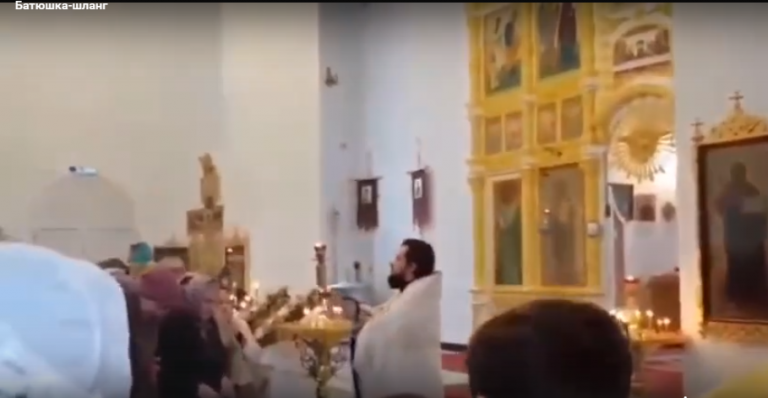 Un sacerdote bendice a sus fieles con la ayuda de una manguera