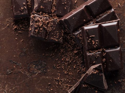 Top view of pieces of chocolate bar with chocolate chips on rust Cómo hacer tu propia tableta de chocolate en casa