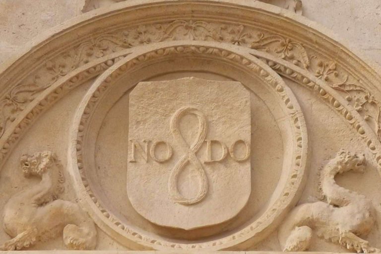 ¿Qué simboliza la inscripción ubicada en diferentes lugares de Sevilla, NO8DO?