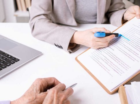 Hands of insurance agent underlining important phrase in document