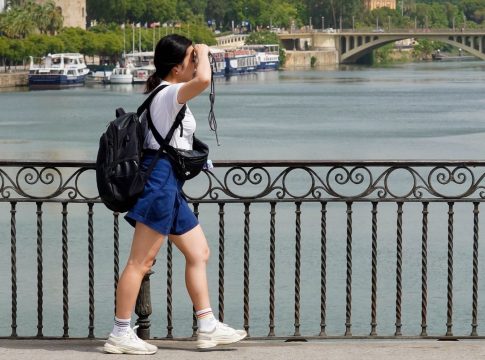 Una persona paseando por el Puente de Triana se protege la cara el día en que la capital está en alerta naranja por el calor