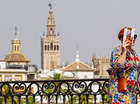 Una persona paseando por el Puente de Triana se protege la cara el día en que la capital está en alerta naranja por el calor , a 19 de julio del 2023.