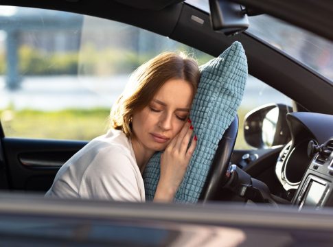 mujer-joven-cansada-conductor-durmiendo-en-la-almohada-en-el-volante-descansando-despues-de-largas-horas-conduciendo-un-coche Dormir en el coche
