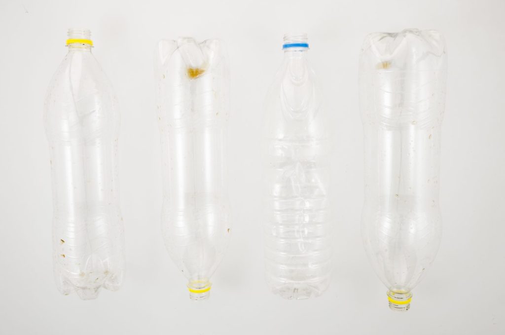 fila de botella de plastico vacia para reciclar sobre superficie blanca