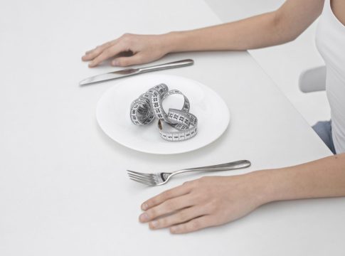 mujer-joven-con-un-trastorno-alimentario-con-una-cinta-metrica-en-el-plato