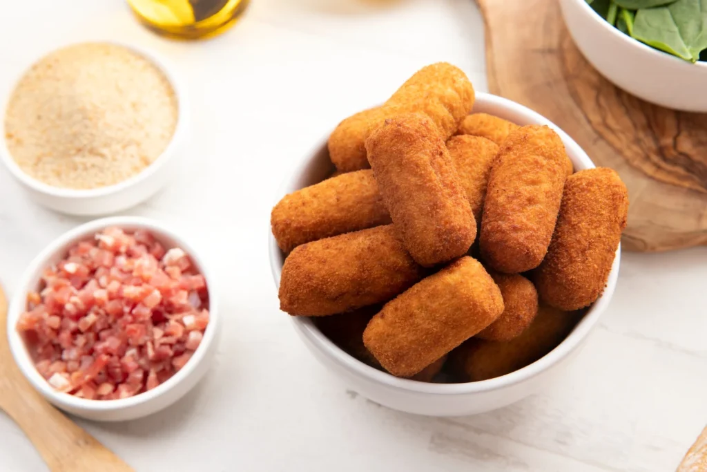 El secreto mejor guardado no es un ingrediente, sino un proceso físico que protege nuestras croquetas. El rebozado dorado y perfecto solo se consigue si no cojen temperatura ambiente. Fuente: Freepik