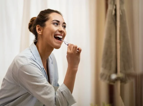 mujer-feliz-limpiandose-los-dientes-con-un-cepillo-de-dientes-por-la-manana