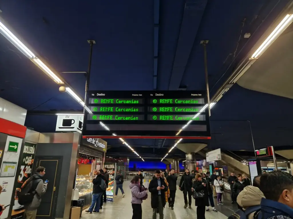 Usuarios de Cercanías esperando a que aparezca algún destino en los paneles de Cercanías en Nuevos Ministerios