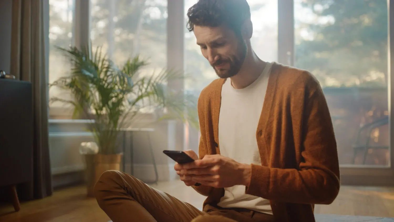 man-using-smartphone-home-does-remote-work-handsome-smiling-male-sitting-floor-works-with-papers-documents-brainstorms-creative-project-with-online-research-sunny-living-room