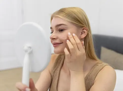 mujer joven usando un producto para el cuidado del rostro Cosmética natural para el rostro