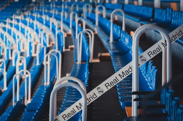 Filas de asientos azules en el icónico Estadio Bernabéu de Madrid, con la marca del Real Madrid.