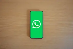 Vista superior de un smartphone que muestra el logo de WhatsApp sobre un fondo de madera, representando tecnología y comunicación.