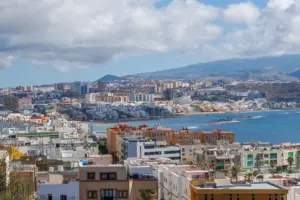 Una vista panorámica del paisaje urbano y la costa de Las Palmas de Gran Canaria bajo un cielo azul.