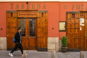 A man walking down a street past a red building