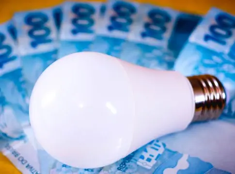 lampara-led-de-diodos-emisores-de-luz-sobre-varias-facturas-de-dinero-real-brasileno-concepto-de-precio-de-electricidad