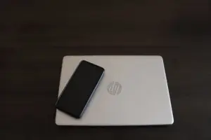Primer plano de un smartphone apoyado en un portátil HP, simbolizando la integración de la tecnología moderna.