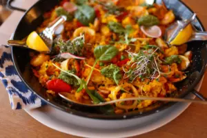 Deliciosa paella vibrante con mariscos, verduras y hierbas en una sartén, lista para servir.