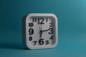 Reloj de pared cuadrado blanco que muestra las 10:10 sobre un fondo azul, perfecto para temas de diseño minimalistas y modernos.
