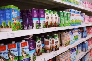 Varios cartones de leche exhibidos en estantes en un pasillo brillante de supermercado.