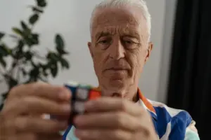 Hombre mayor concentrado en resolver un Cubo Rubik, demostrando concentración y agilidad mental.