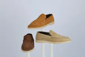Tres mocasines de gamuza expuestos en stands, resaltando el estilo y la elegancia.