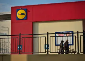 Gente caminando frente a un supermercado Lidl con señalización clara en un día soleado.