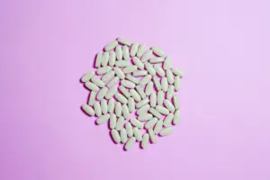 Un conjunto de píldoras blancas sobre una superficie púrpura, destacando temas farmacéuticos.