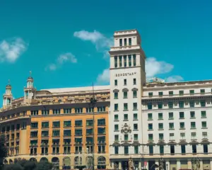 Fachada de edificio neoclásico en soleada Barcelona, mostrando estilo arquitectónico histórico.
