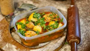 Guiso de pollo casero aromático con hierbas y verduras en un recipiente de plástico.