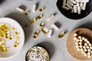 Una variedad de pastillas y cápsulas dispuestas sobre una superficie gris, mostrando salud y bienestar.