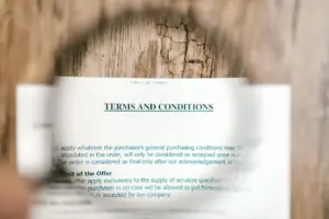 Lupa enfocando el documento de términos y condiciones sobre una superficie de madera.
